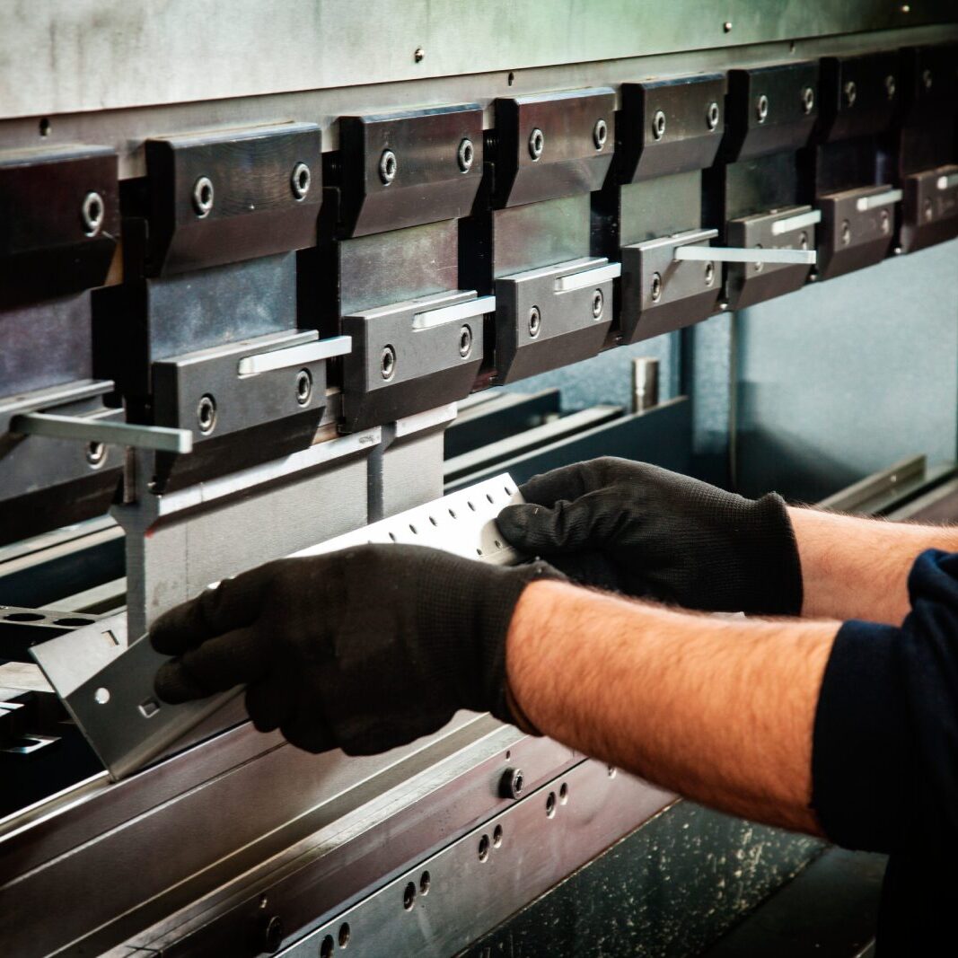 Person operating industrial metal bending machine.